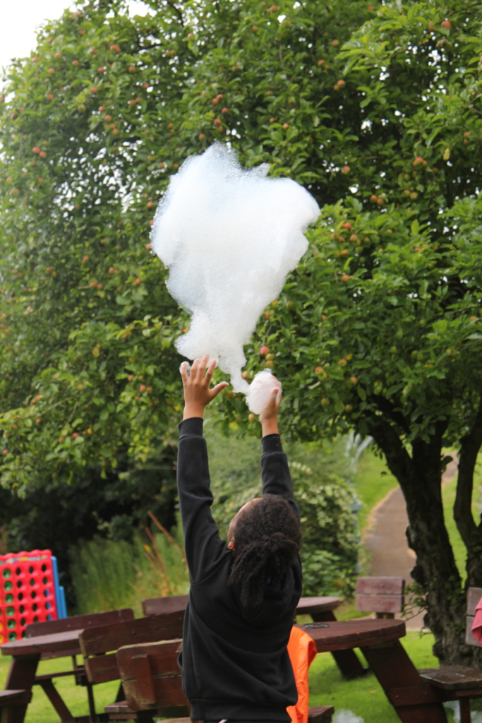 A child looking up to the sky letting go of a giant bubble