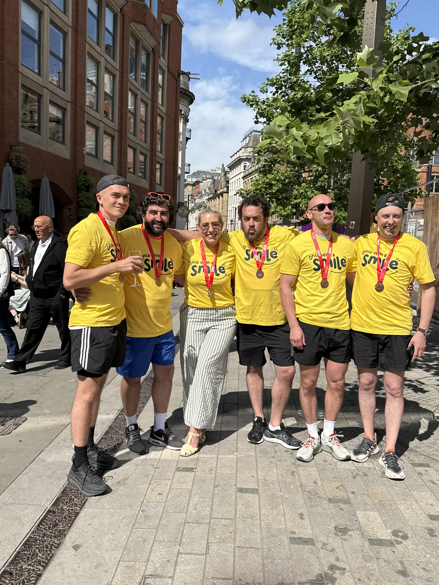 A group of people in yellow charity t-shirts smiling to camera
